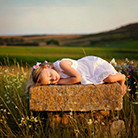 A child sleeping on a stone bench in a field

Description automatically generated